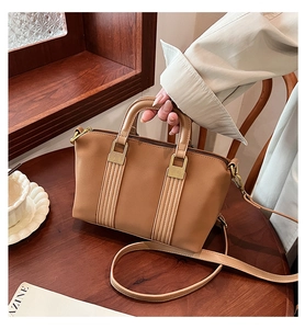 Close-up of brown faux leather Boston tote bag with gold hardware on wooden table