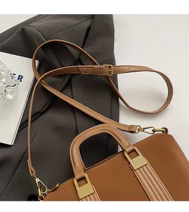 Detail of brown leather tote bag with gold rectangular clasp and adjustable shoulder strap