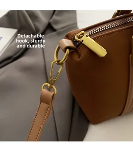 Detail of premium brown leather tote with golden zipper and detachable metal hook clip