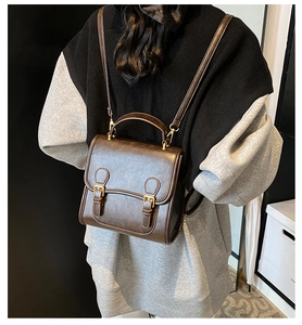 Detail of vintage dark brown leather backpack with gold buckles and adjustable straps