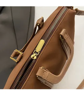 Close-up of smooth gold zipper and durable leather handles on a tan tote bag