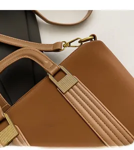 Detail of gold metal hardware with vertical stripe engraving on brown leather tote bag