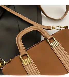 Close-up of caramel brown leather tote handle with detailed gold metal hardware connectors