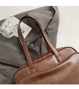 Detail of brown leather Boston bag with visible fine stitching and vintage grain texture