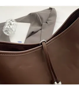 Dettaglio dei raccordi in metallo argento e cuciture sulla borsa in pelle marrone scuro