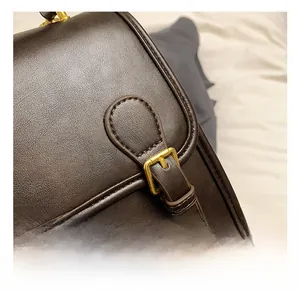 Close-up of vintage gold buckle and fine stitching on dark brown leather backpack
