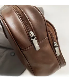Detail of smooth double metal zippers and stitching on a brown Boston leather handbag