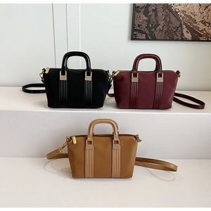 Boston crossbody bags in black, burgundy and caramel brown displayed on white stairs