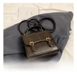 Detail shot of vintage dark brown faux leather bag with double buckle gold hardware