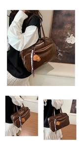 Close-up of vintage brown tote bag featuring a cute plush puppy charm and front zipper detail