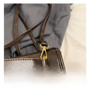 Detailed close-up of premium gold-tone metal hook and brown leather strap stitching