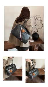 Detailed view of black matte leather tote bag with a brown plush bear charm and ribbon