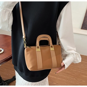 Detailed view of brown tote bag featuring decorative stripes and gold hardware