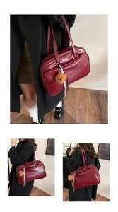Detail of dark red faux leather Boston bag with teddy bear charm and gold logo