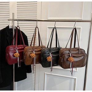 Detail view of four retro Boston handbags in matte leather with plush bear charms