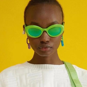 Neon green thick frame oval cat eye sunglasses with green lenses on model with yellow background