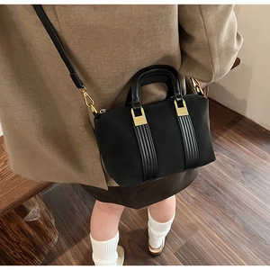 Detail shot of a black leather Boston bag with gold hardware and removable shoulder strap