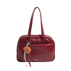 Large burgundy Boston bag with glossy finish and cute teddy charm on white background