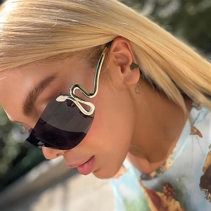 Lunettes de soleil Y2K enveloppantes avec branches serpent dorées sur un mannequin femme