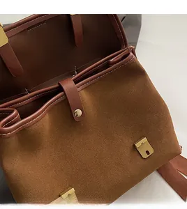 Close-up of golden metal buckle and brown matte suede texture on vintage backpack