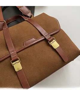 Detail of vintage brown suede bag with fine white stitching and golden metal clasp buckle