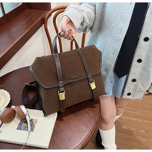 Detail of dark brown vintage briefcase with buckle straps and woven strap in room setting