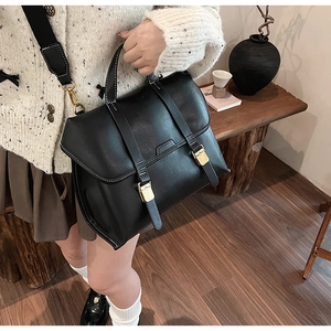 Detail of vintage black leather briefcase handbag with gold buckles and wide shoulder strap