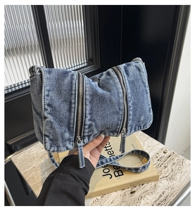 Detail of blue denim shoulder bag showing retro washed texture and metal zippers