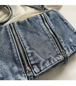 Detail of blue washed denim tote bag showing snowflake texture and silver metal zippers