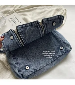 Detail of the magnetic snap closure and texture of the washed blue denim tote bag