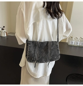 Detail view of washed denim crossbody bag featuring stylish parallel vertical zippers