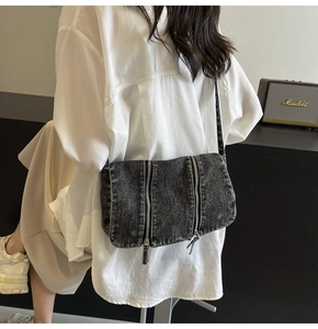 Detail of vintage gray denim crossbody bag with three vertical decorative silver zippers