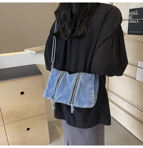 Blue denim crossbody bag detail on model featuring decorative dual vertical zippers