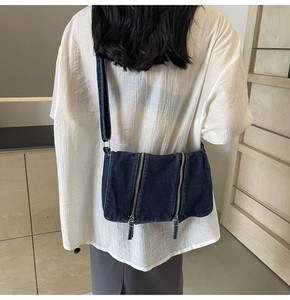 Detail view of a vintage wash denim crossbody bag worn by a model in a casual setting
