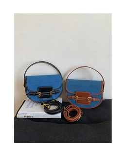 Detail view of denim saddle bags with brown and black leather trim and gold buckles