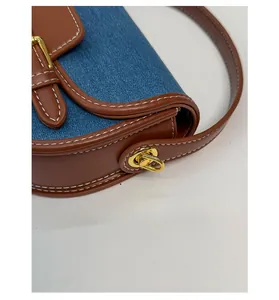 Detailed close-up of leather stitching and blue denim fabric on the saddle bag