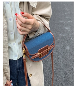 Close-up of retro denim saddle bag with brown leather trim and golden metal buckle details