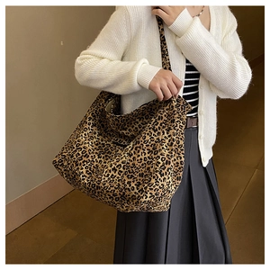 Detail view of leopard print canvas tote bag styled with a white knit cardigan