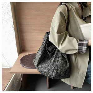 Detailed side view of a large leopard print tote bag worn on shoulder by a model