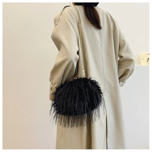 Close-up of black feather shoulder bag with gold bead chain on beige trench coat