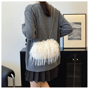 Detail view of a white fluffy turkey feather shoulder bag with a gold metal chain strap