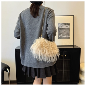 Detail of a fluffy beige feather shoulder bag with a gold metal ball chain strap
