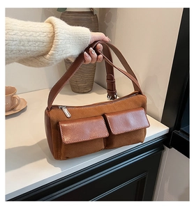 Macro shot of brown suede and leather baguette bag with dual square front pockets