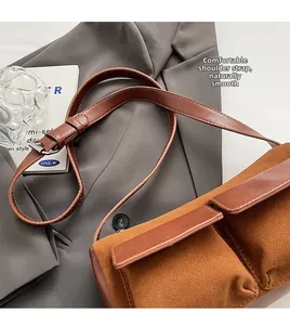 Detail of adjustable brown leather shoulder strap on suede baguette bag with buckle