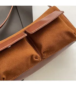 Detail of brown faux suede baguette bag with leather stitching and front pocket flap