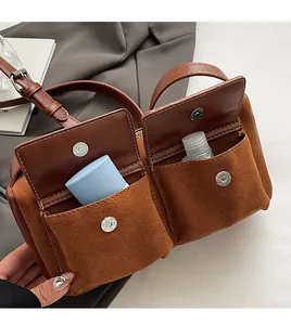 Detail of suede baguette bag with dual front pockets and magnetic silver buckles
