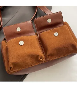 Detail of brown suede shoulder bag featuring two front magnetic pockets and silver hardware