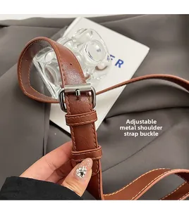 Detail of adjustable brown leather strap with silver buckle on a stylish handbag