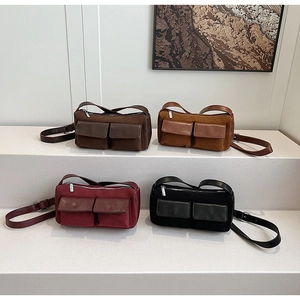 Four suede baguette bags in brown, caramel, wine red and black on a white tiered display