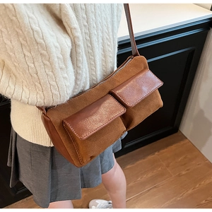 Detail of caramel suede baguette bag with leather pockets worn with a knit sweater
